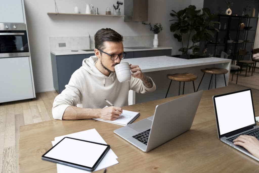 Sistema de PABX Virtual em Nuvem para Empresas - Homem trabalhando em casa, no escritório, enquanto toma uma bebida.